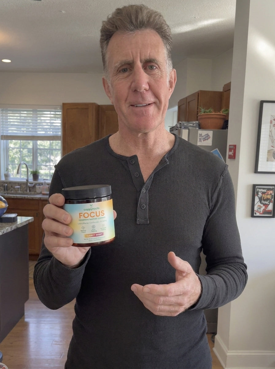 A man in a dark henley holds a jar of CappyRoots Focus gummies in a kitchen
